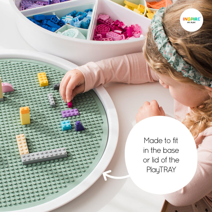 Child carefully placing a building block on to the building block mat